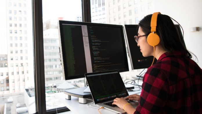 woman with headphones looking at computer online coding tools